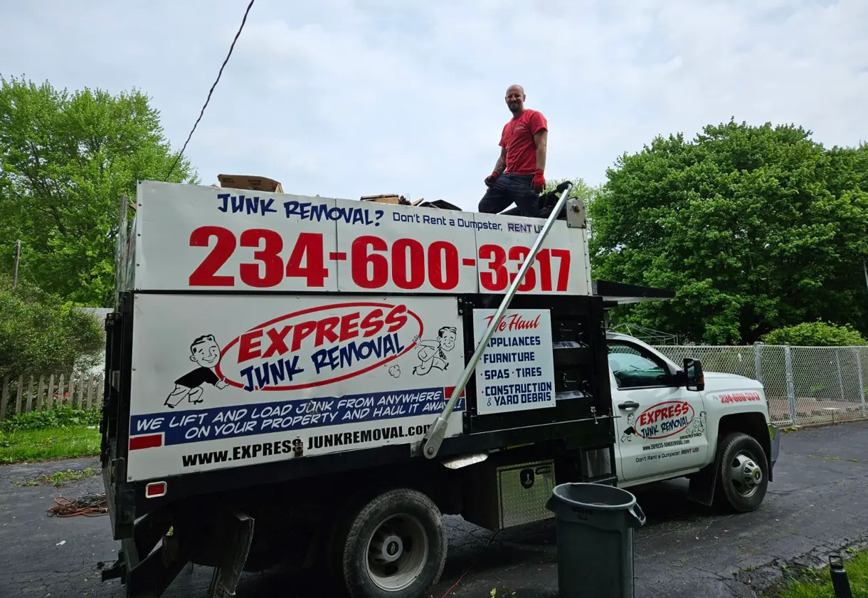 Two Express Junk Removal employees standing with a very satisfied customer.