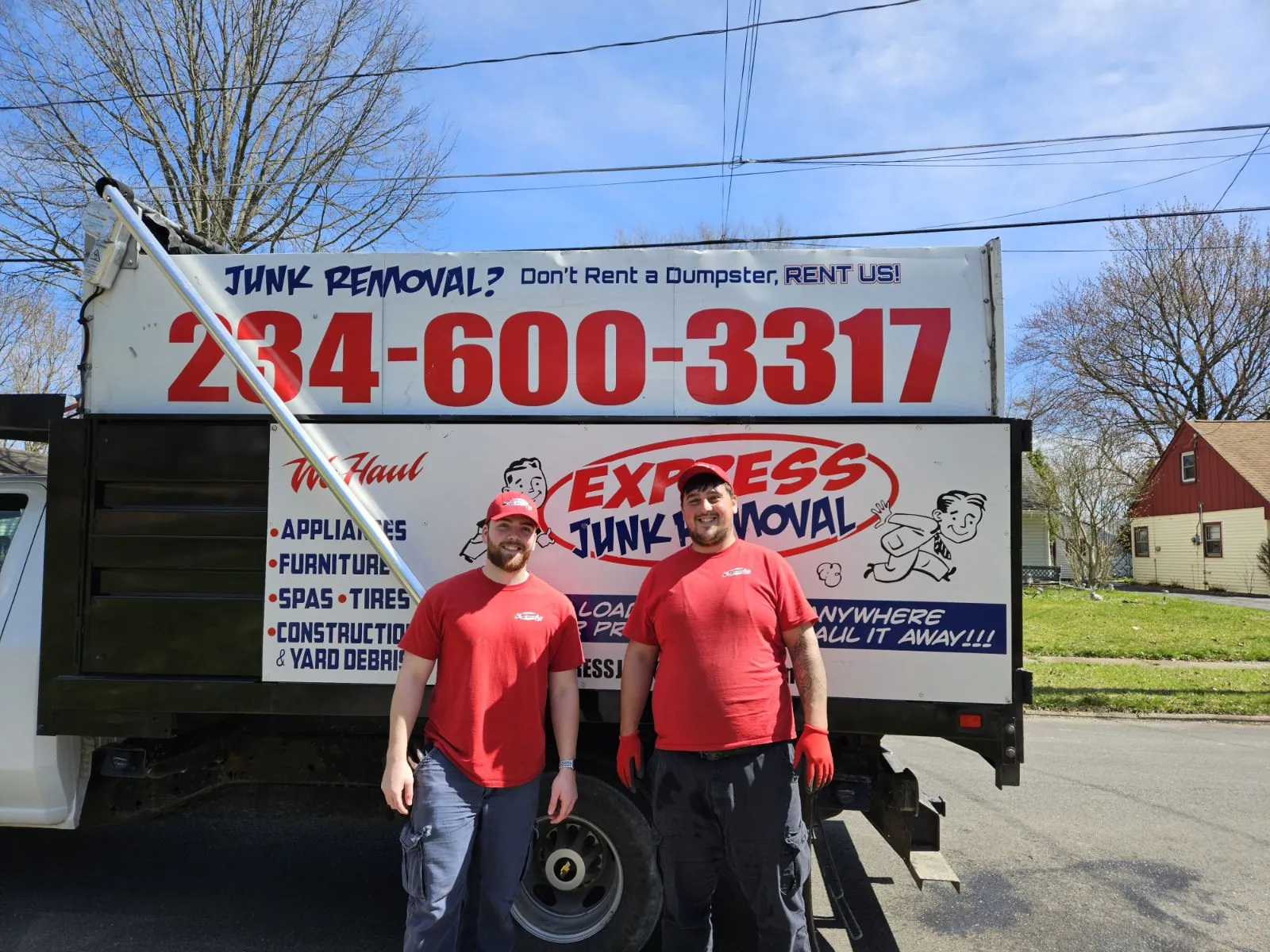 Two smiling Express Junk Removal crew members in front of their truck