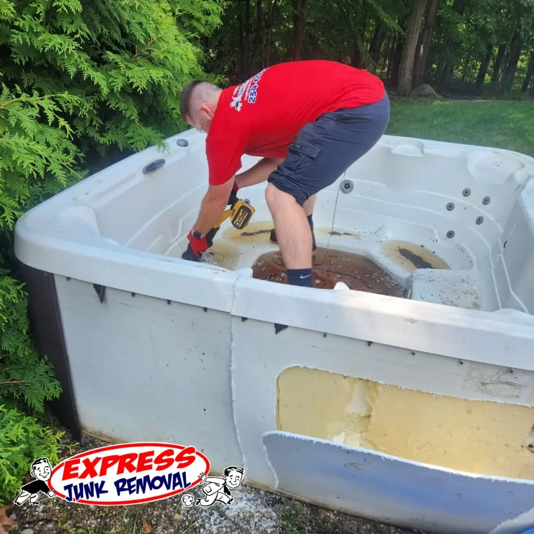 Express Junk Removal crew member cutting apart an old hot tub for removal
