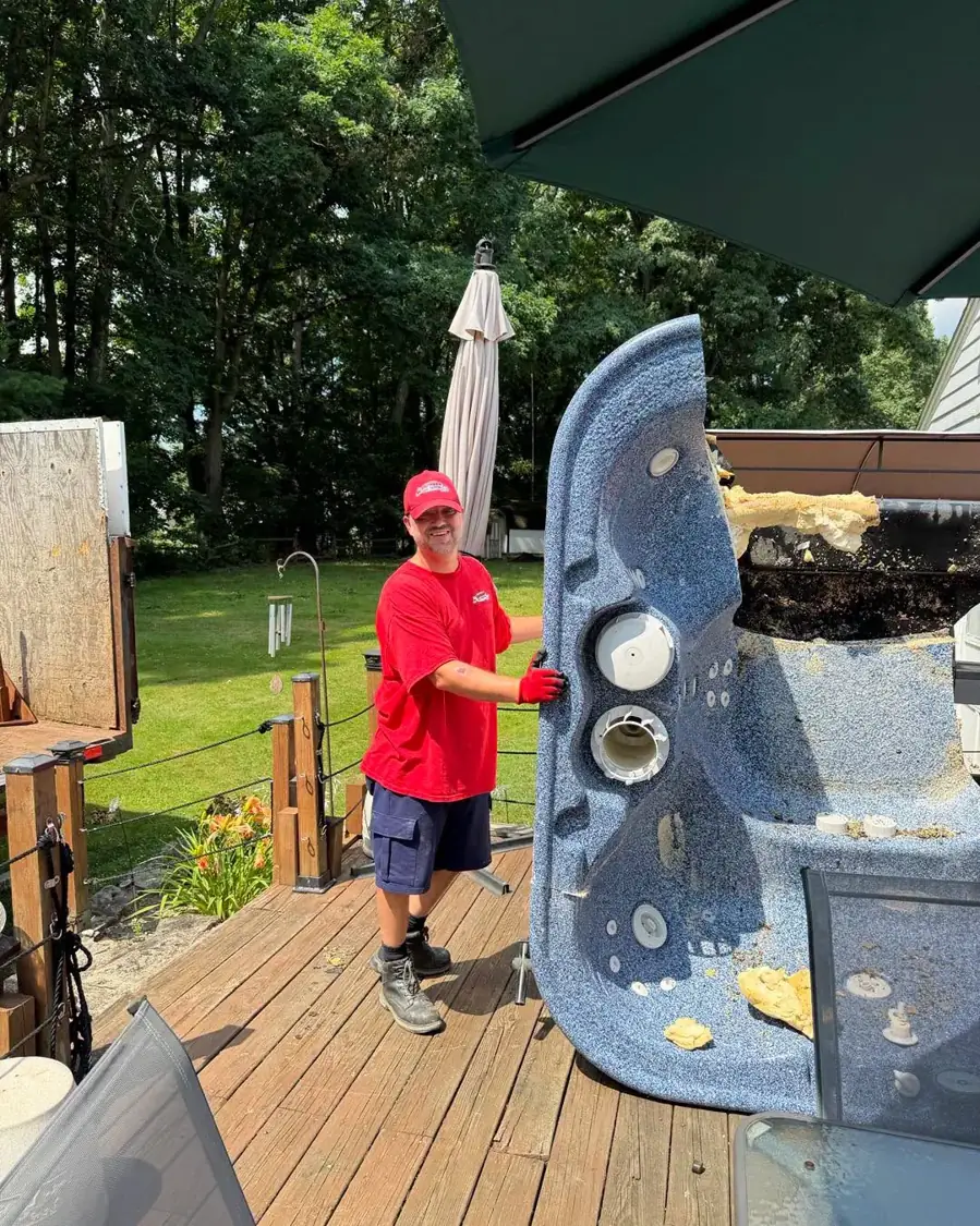 Express Junk Removal crew member standing a cut-apart hot tub shell on end on a backyard deck