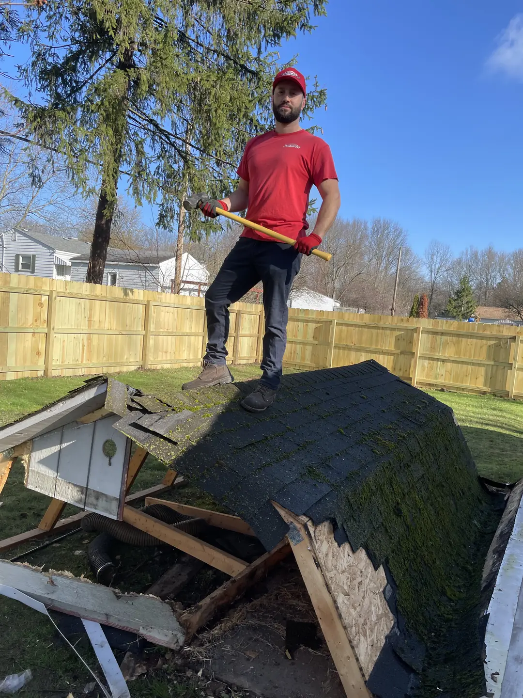 Express Junk Removal crew member standing on the roof of a shed being torn down