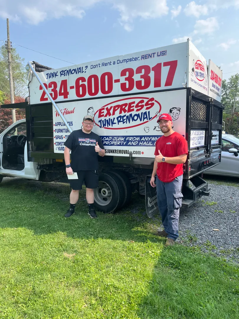 Happy customer giving a thumbs up next to an Express Junk Removal crew member and truck