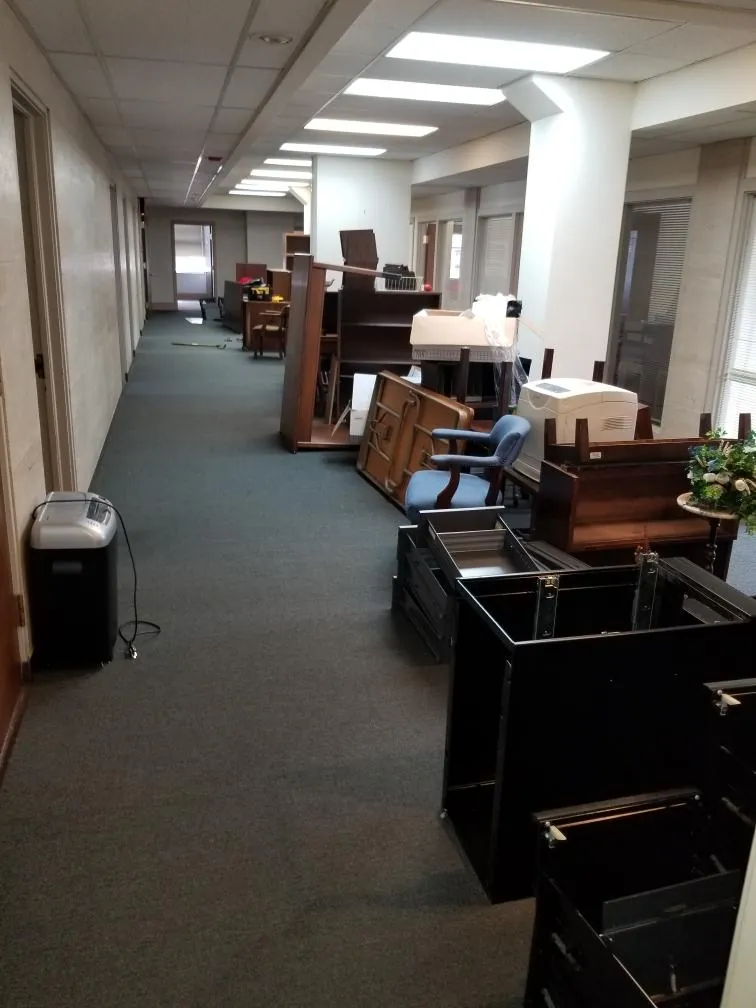 Office hallway lined with desks, filing cabinets, chairs and a printer before an Express Junk Removal cleanout